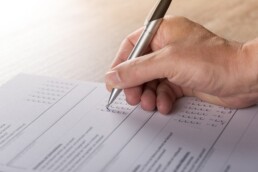 A hand holding a pen filling out a survey, similar to the one about immigration in Canada.