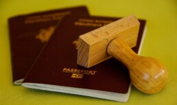 A set of passports and travel documents rest below a stamp, ready for validation during the flagpoling process.