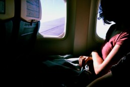 A woman looks out the window of an airplane in flight.