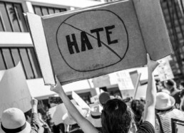 Woman at a protest holds a no hate sign