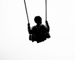 Black and white photo of a boy in a swing