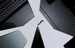 Canadian flag shown from below a flagpole with skyscrapers in the distance
