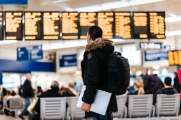 Man stands in the airport looking at terminal and flight chart