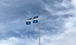 Quebec flag flies with a blue, cloudy sky in the background