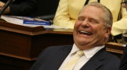 Doug Ford laughs in his chair in Parliament