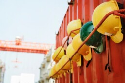 yellow and green hardhats lined up along a metal container