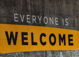 'Everyone is Welcome' Painted on concrete wall surrounded by graffiti