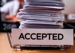 Stack of papers in basket with 'Accepted' Sign
