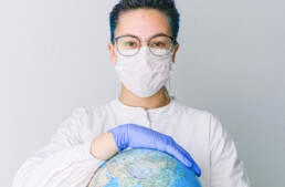 person-with-a-face-mask-and-latex-gloves-holding-a-globe